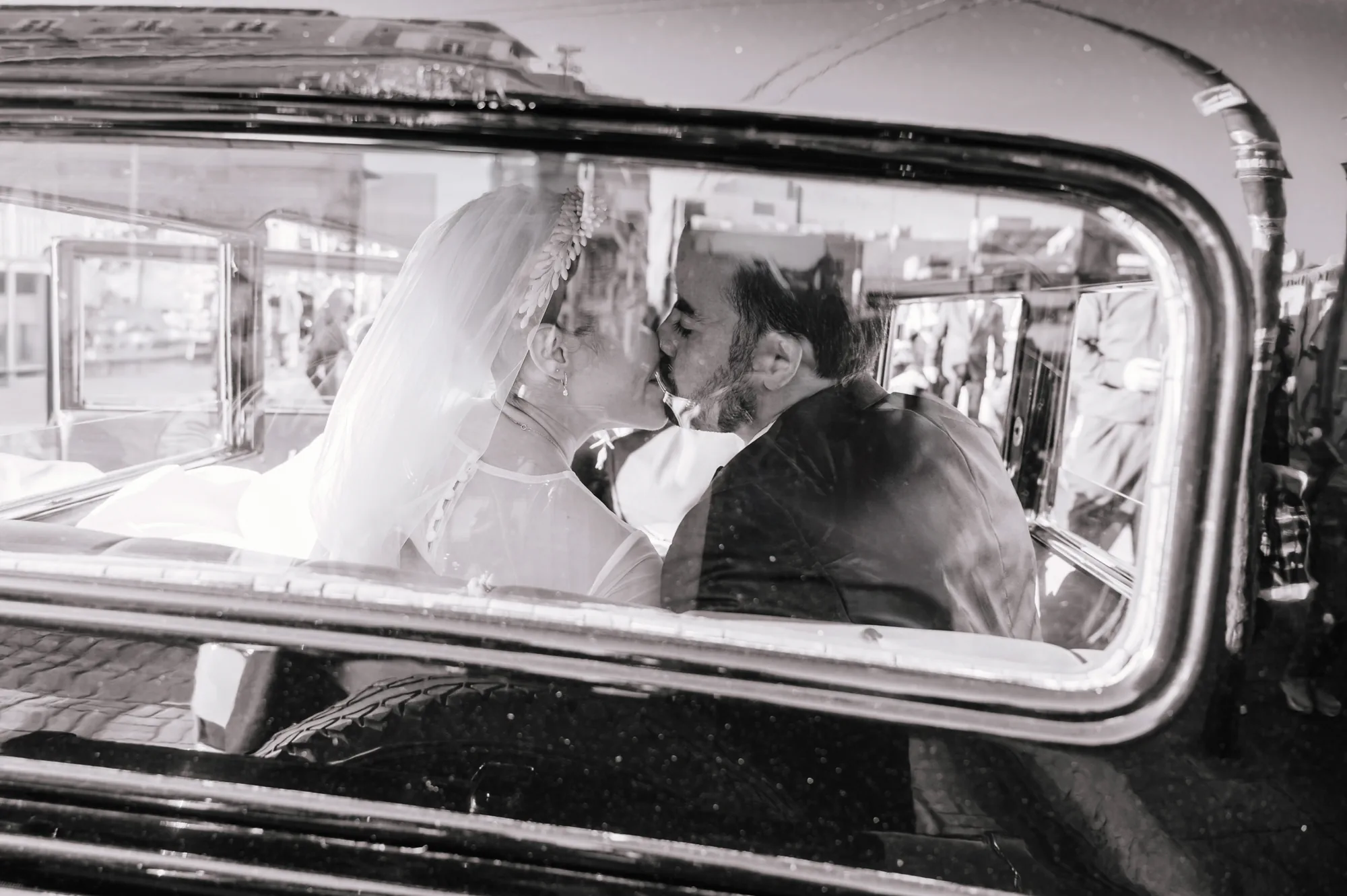 Novios reflejados dentro de un automóvil clásico en una fotografía en blanco y negro