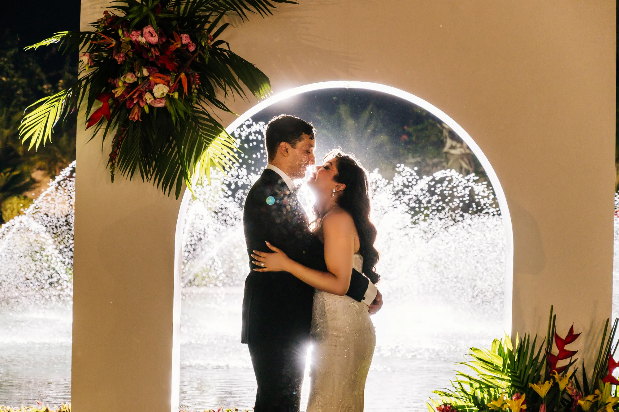 Novios abrazándose bajo un arco circular iluminado durante su celebración