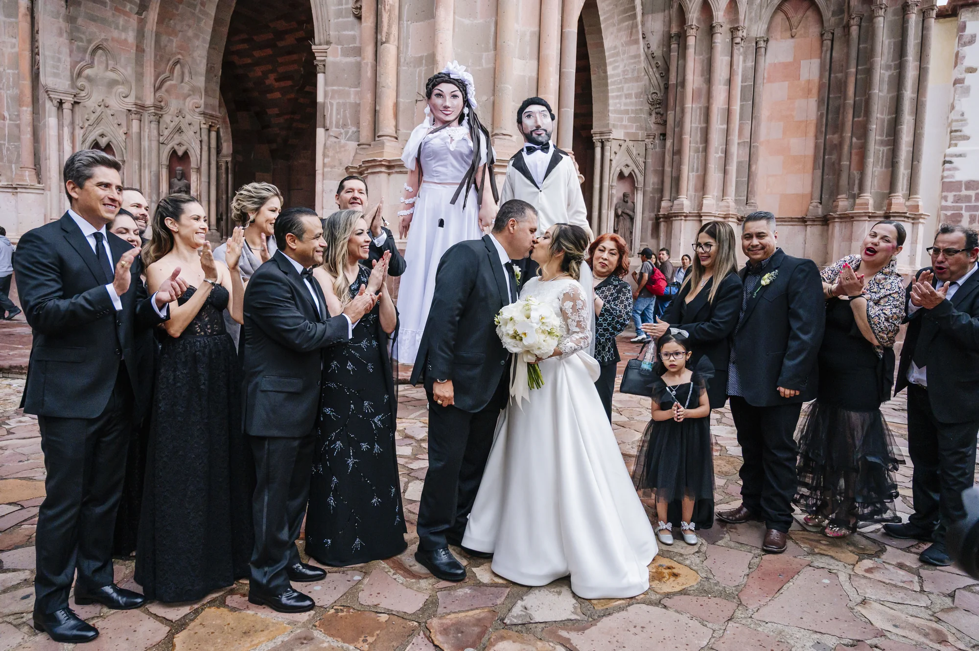 Novios celebrando con sus invitados y mojigangas frente a una iglesia de San Miguel de Allende
