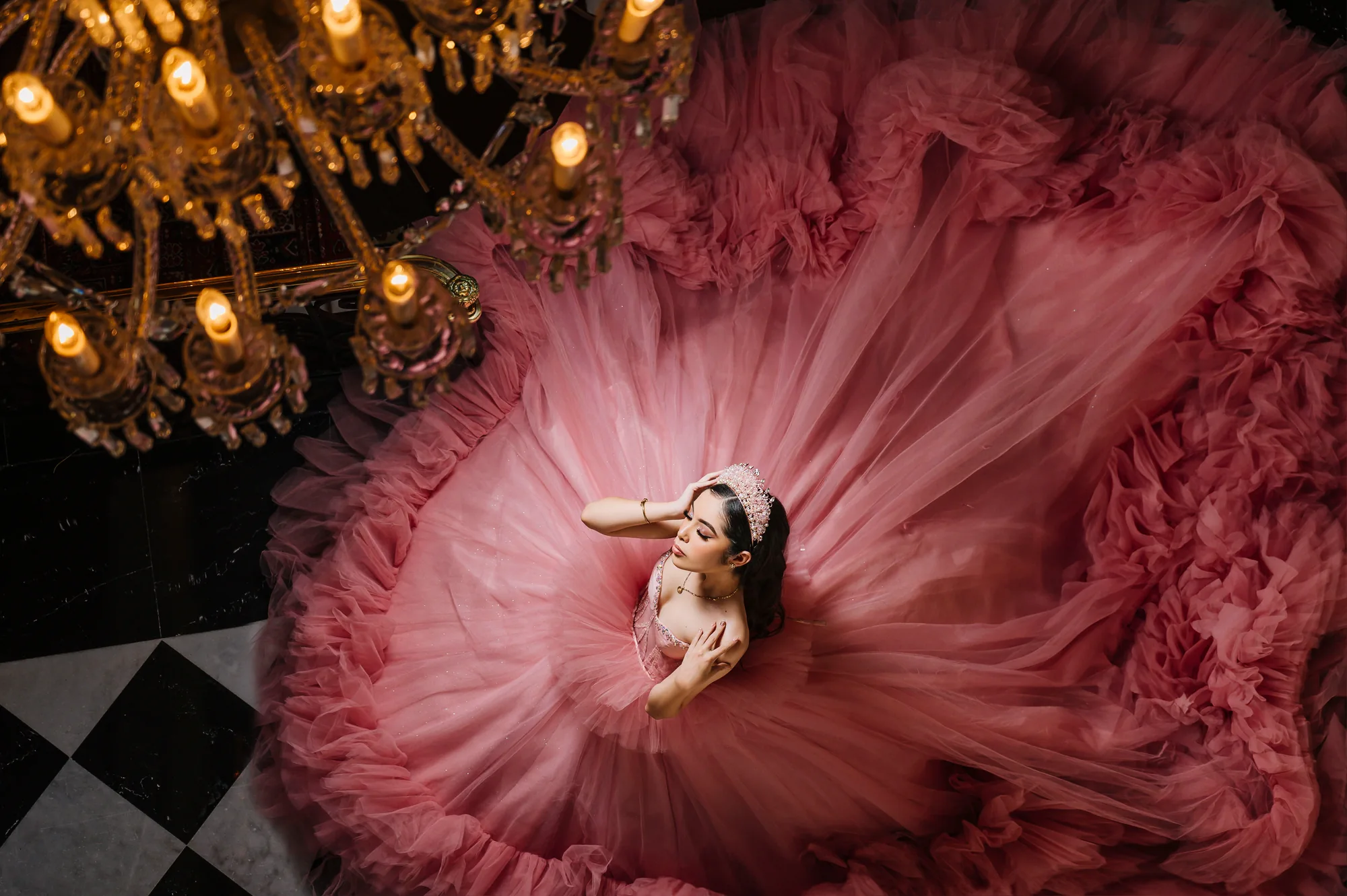 Quinceañera recostada con su vestido rosa extendido en una composición editorial