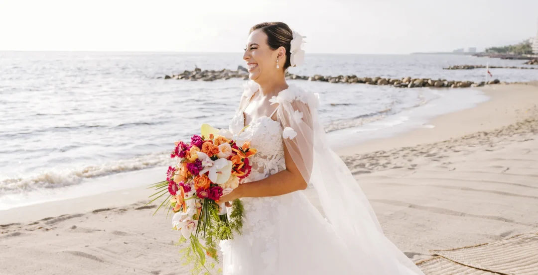 Novia con su ramo caminando frente al mar en Puerto Vallarta