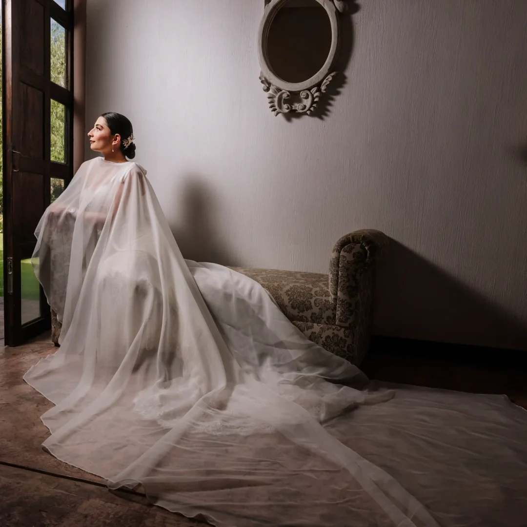 Novia junto a una ventana con el velo extendido durante los preparativos