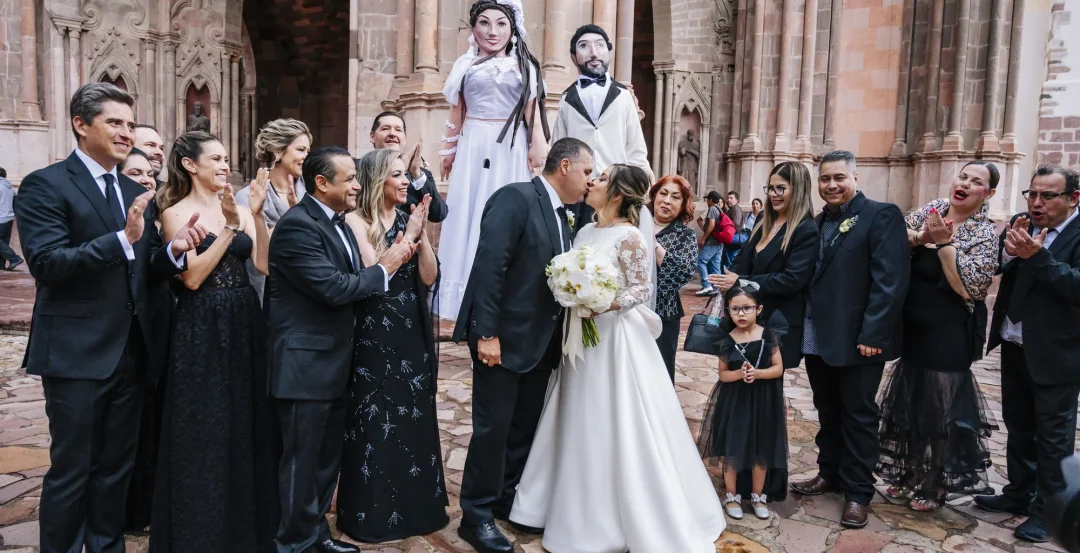 Novios celebrando con sus invitados y mojigangas frente a una iglesia de San Miguel de Allende